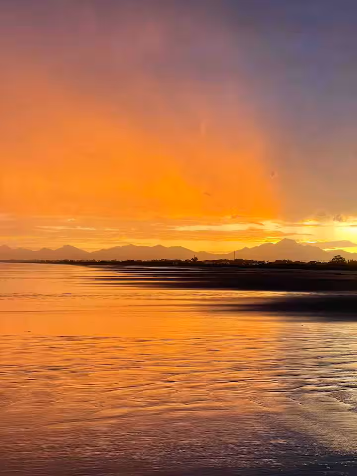 Pôr do sol laranja intenso sobre a maré baixa em Pontal do Sul